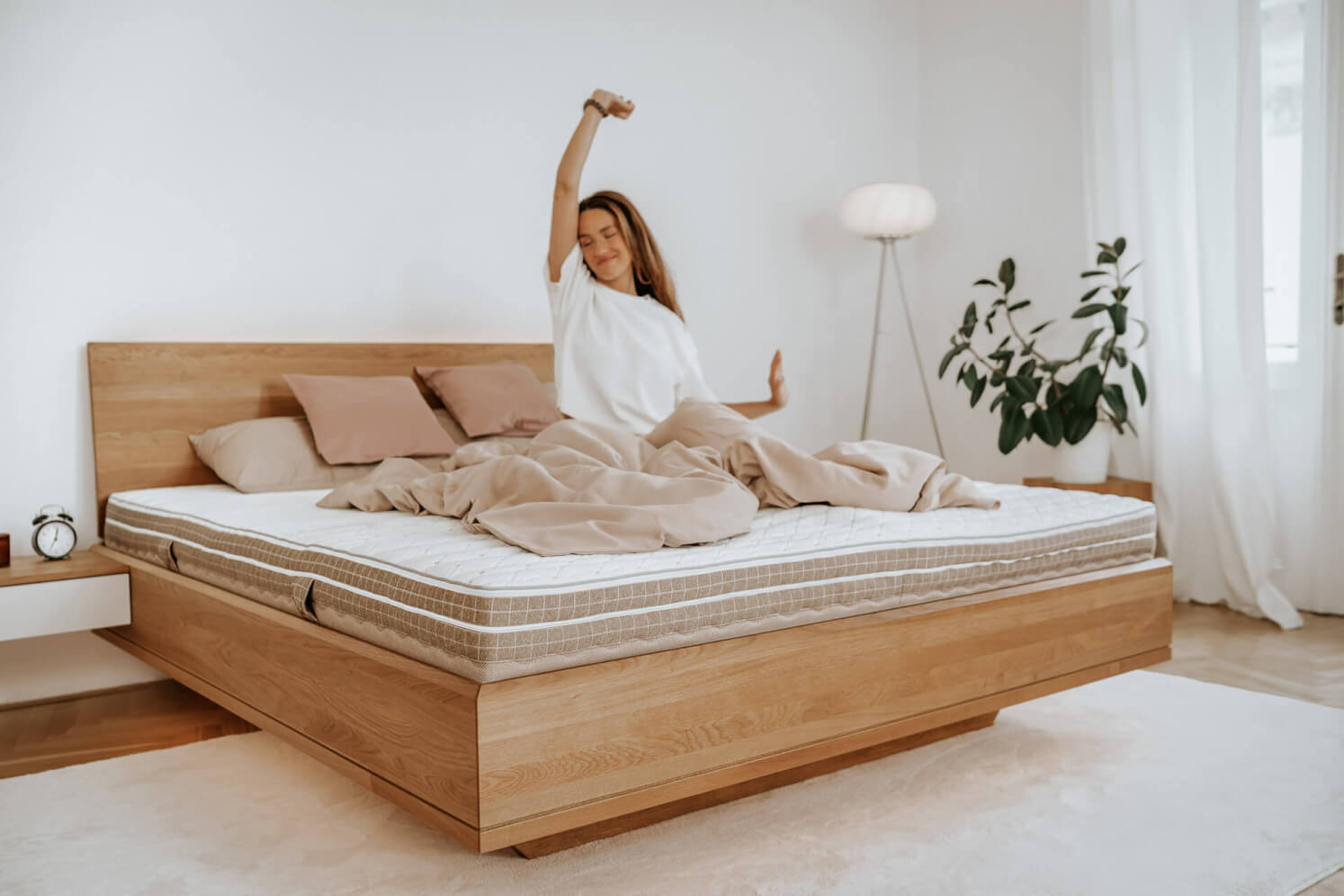Eine Frau steht von einer SÁRA Spirit Doppelmatratze mit Morrison-Bezug auf. Die Maße der Matratze auf dem Foto betragen 180 x 200 x 22 cm.